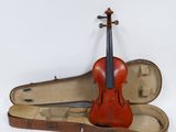 un vieux violon repose dans son étui, posé sur une surface blanche