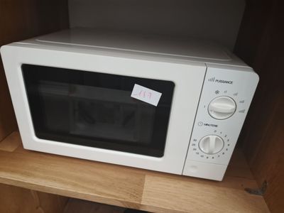un micro-ondes blanc posé sur une étagère en bois dans un placard