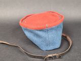 a small blue and red bag with a brown strap
