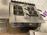 stainless steel counter top with three deep fryers on each side of it