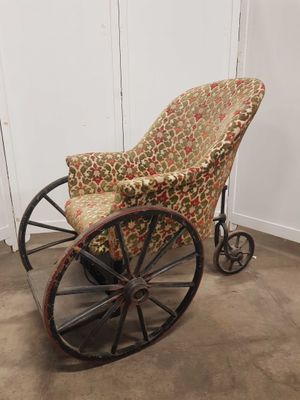un fauteuil à bascule à l'ancienne, avec une assise rembourrée à motifs floraux et des roulettes
