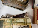 a pile of old postcards on a table with a bottle of wine