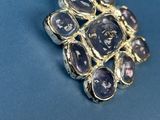 a close up of a ring with purple stones on a blue surface
