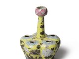 un vase jaune surmonté d'une fleur rose