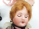 a close up of a doll with a pink bow on it ' s head