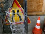 un panier en fil de fer avec une pancarte et des cônes de signalisation posés par terre