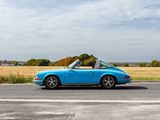 blue porsche speedster parked on the side of the road in front of a field