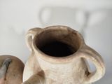 a small brown vase with a handle and a lid on a table