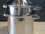 une casserole en argent avec un couvercle, posée sur une table en bois