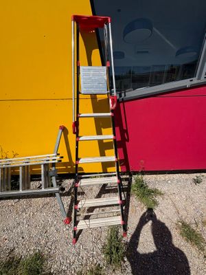 a red ladder leaning against a yellow wall next to a ladder