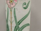 a white vase with pink flowers on it on a table