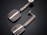 a pair of silver and brown stone earrings on a black surface