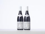 two bottles of red wine sitting on top of a white table