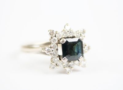 a close up of a ring with a blue diamond surrounded by white diamonds