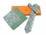 Coffret cadeau comprenant une cravate et une pochette à motifs floraux bleus et verts, présenté dans une boîte orange