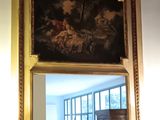 un miroir orné d'une peinture, dans une pièce