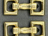 pair of brass plated buckles on a gray surface
