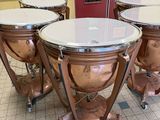 several copper colored musical instruments sitting on top of a tiled floor