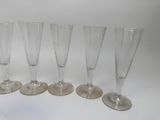 six empty wine glasses lined up on a white surface