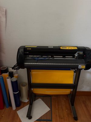 une machine posée par terre à côté de quelques rouleaux de papier
