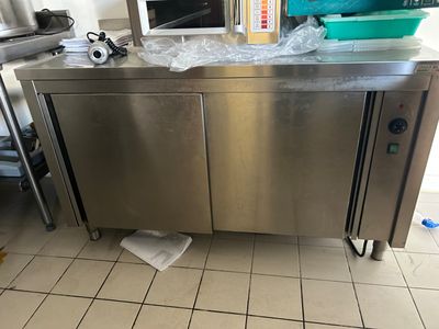 a stainless steel counter in a kitchen with a lot of clutter on the floor
