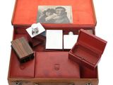 a red suitcase with a note pad and other items in it