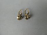 une paire de boucles d'oreilles en or sur une surface blanche