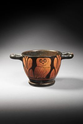 an old black and orange vase with an owl on it ' s side