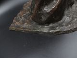 a bronze statue of a woman sitting on top of a rock