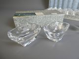 une paire de cendriers en verre transparent posés sur une table, à côté d'un paquet de cigarettes