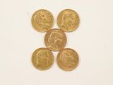 quatre types différents de pièces d'or sont disposés sur une surface blanche