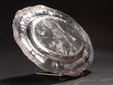 a silver plate on a metal stand on a black background