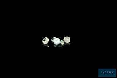 two white pearls are sitting on a black surface in the dark