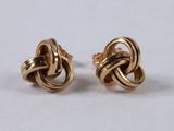 a pair of gold tone earrings with a knot design