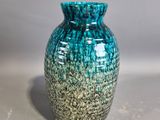 a blue and green vase sitting on a white surface