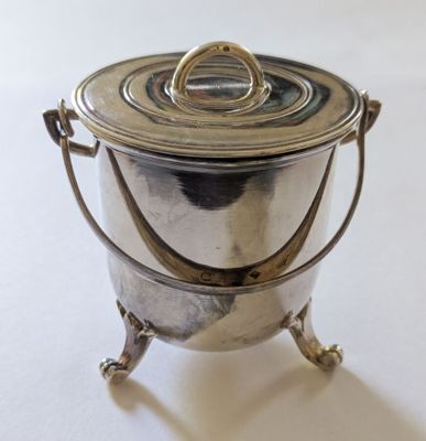 une casserole en argent avec une poignée, posée sur une table blanche