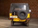 a yellow jeep parked in front of a brick wall
