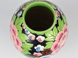 a green vase with flowers on it on a white surface