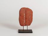 an image of a red stone sculpture on a wooden stand