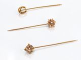 three pairs of gold and diamond ear pins on a white surface