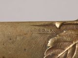 a close up of a gold plated knife with a leaf on it