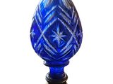une image représentant un vase en verre bleu posé sur un socle en bois