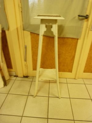 a small white table in the corner of a bathroom