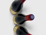three bottles of red wine are lined up on a white surface