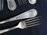 a lot of silver spoons and forks on a black table