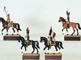 quatre figurines représentant des hommes en uniforme à cheval, posées sur des socles en bois