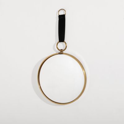 un miroir plaqué or suspendu à une lanière en cuir noir