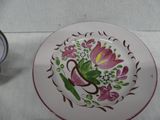 a plate with a flower design on it next to a clock