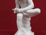 statue of a man sitting on a rock with his hands on his knees