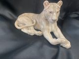 une figurine représentant un lion couché sur un tissu noir